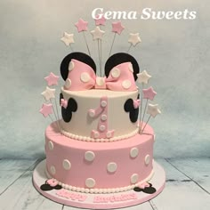 a pink and white cake with minnie mouse ears on top is decorated with polka dots