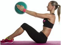 a woman holding a medicine ball in her right hand and stretching it on the floor