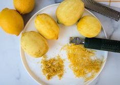 a white plate topped with lemons next to a knife and some grated cheese