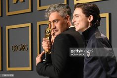 two men holding an oscar statue and posing for the camera with their arms around each other