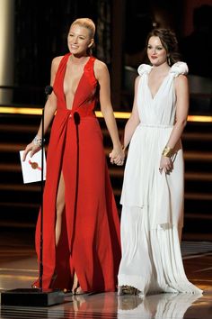 two women standing next to each other on a stage with one holding the hand of another woman