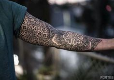 a person with a tattoo on their arm holding something in his hand and looking off to the side