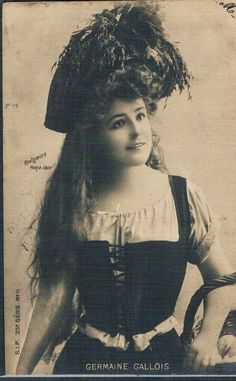 an old black and white photo of a woman with long hair wearing a dress and hat