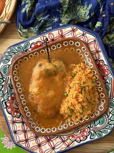 a plate with rice, meat and gravy on it next to other food items