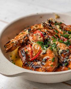 a white bowl filled with cooked shrimp and garnished with parsley on top