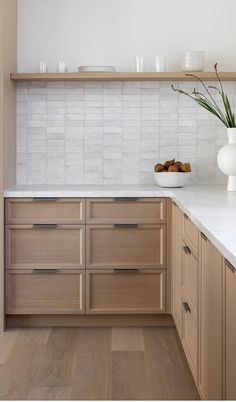 a kitchen with wooden cabinets and white marble counter tops, along with a vase filled with flowers