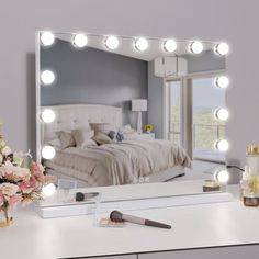 a vanity mirror with lights on it and a bouquet of flowers in the foreground