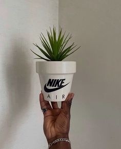 a hand holding up a white nike planter with the word air printed on it