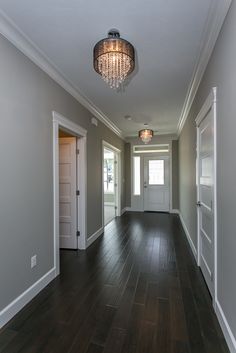 an empty room with hard wood floors and a chandelier hanging from the ceiling