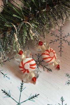 two candy canes are hanging from a christmas tree branch with snowflakes in the background