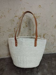 "White sisal tote bag DIMENSIONS Bottom width: 10\"/25.5cm Top width: 14\"/35.56cm Depth: 10\"/25.5cm Straps: 15\"/38cm SHIPPING All orders ship via DHL Express (3-5) days delivery time." Eco-friendly White Bag With Natural Fiber, Eco-friendly White Bag In Natural Fiber, Everyday Basket Crochet Bag, White Tote Bag In Natural Fiber, Market Tote Bag With Rolled Handles, White Natural Fiber Tote Beach Bag, White Natural Fiber Tote Bag, Handwoven Tote Bucket Bag, White Woven Crochet Bag In Natural Fiber