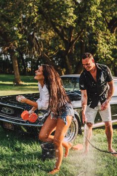 a man and woman playing in the water next to a car