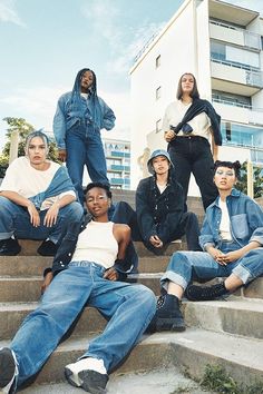 a group of young people sitting on the steps in front of an apartment building, posing for a photo