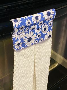 a blue and white towel hanging from the side of an oven door with flowers on it