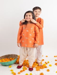 Girls Dress: Orange chanderi embroidered yoke kurta set with dhoti pants. Boys Kurta Set: Rust orange bird embroidered chanderi kurta set with white cotton pajama Color: Orange Fabric: Chanderi and Cotton Note: The product will be delivered within 2-4 weeks of order placed Wash Care - Dry clean only No returns and Exchange. Measure before ordering to avoid any returns. Measurements: SIZE CHART FOR BOYS KURTA SET CHEST ROUND WAIST ROUND KURTA LENGTH SLEEVE LENGTH BOTTOM LENGTH JACKET LENGTH SHIRT Embroidered Orange Sets For Navratri, Orange Embroidered Sets For Diwali, Orange Kurta With Dori Work For Eid, Orange Chikankari Embroidery Set For Diwali, Orange Chikankari Embroidered Sets For Festivals, Orange Dabka Kurta For Navratri, Festive Orange Sets With Chikankari Embroidery, Orange Dabka Sets For Festivals, Embroidered Orange Kurta For Diwali