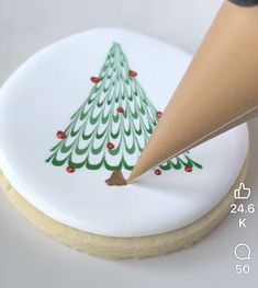 a cookie with a christmas tree painted on it and a pencil sticking into the top