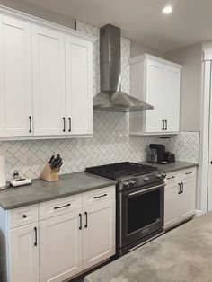 a kitchen with white cabinets and stainless steel stove top oven in the middle of it