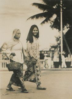 an old photo of two women walking down the street