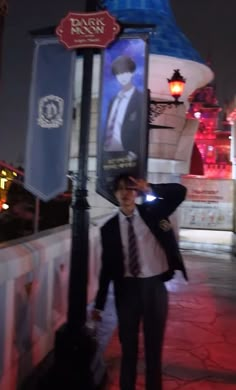 a man in a suit and tie standing next to a lamp post with a sign on it