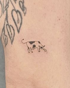 a small cow tattoo on the side of a man's right leg and foot