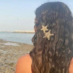 the back of a woman's head with long hair and two gold stars on it