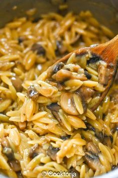 a wooden spoon is full of pasta and mushrooms