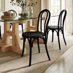 a dining room table with four chairs and a vase on top of the table in front of it