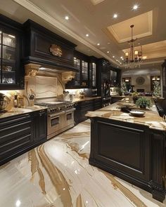 a large kitchen with marble counter tops and black cabinets, along with chandeliers