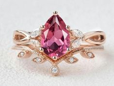 a close up of a ring with a red stone and diamonds on the side,