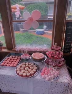 a table topped with lots of desserts next to a window