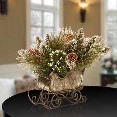 a small sleigh filled with pine cones and baby's breath on top of a table