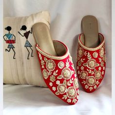 a pair of red slippers sitting next to a pillow