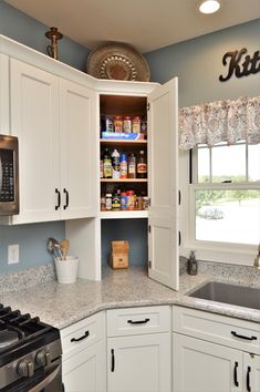 a kitchen with white cupboards and granite counter tops next to a stove top oven