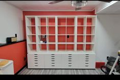 an office with orange walls and white cabinets