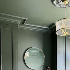 a bathroom with green walls and a round mirror on the wall