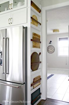 a kitchen with white cabinets and stainless steel refrigerator freezer combo in the center, open shelves on both sides