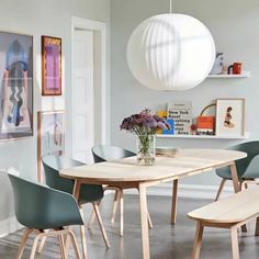 a dining room table with chairs and a vase filled with flowers on top of it