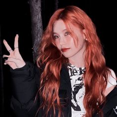 a woman with long red hair is making the peace sign