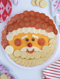 a platter filled with cheese and crackers, meat patties, and a face made to look like santa clause