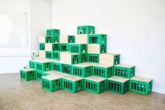 a pile of green crates sitting on top of a floor next to a white wall