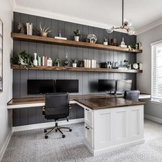 a home office with two desks and bookshelves on the wall above them