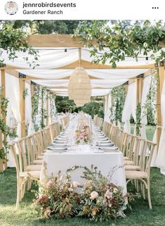 an outdoor table set up with flowers and greenery