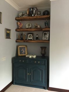 there is a blue cabinet in the corner with pictures on it and other items on top