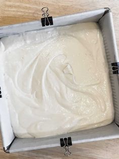 a pan filled with white batter sitting on top of a wooden table next to a knife