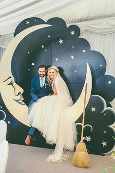 a man and woman sitting on top of a moon in front of a white backdrop