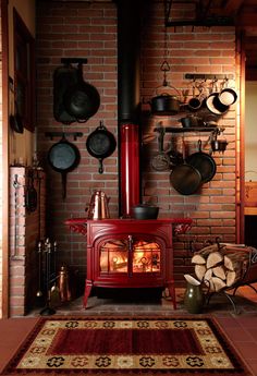 a red stove sitting in the middle of a kitchen next to a pile of wood