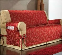 a red and beige couch sitting on top of a wooden floor next to a rug