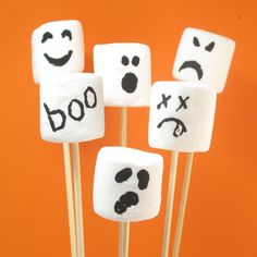 marshmallows with faces drawn on them sitting in front of an orange background