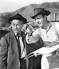 two men standing next to each other in front of mountains