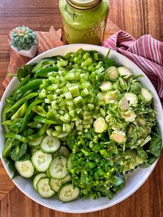 a white bowl filled with cucumbers and green beans on top of a wooden table